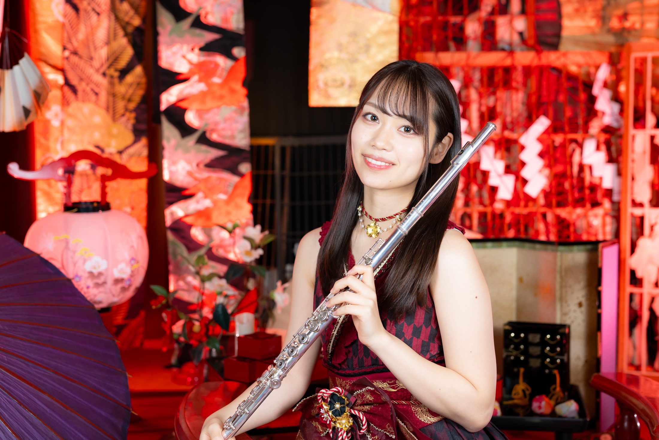 KATOROLL holding a flute in front of red Japanese umbrellas and lanterns
